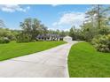 View of the house with a long concrete driveway, lush green lawn, and mature trees at 23647 Seneca Ridge Ct, Christmas, FL 32709