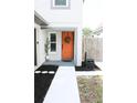 Welcoming front entrance features a bright orange door, a wreath, and fresh landscaping at 312 W Hull Ave, Oakland, FL 34760