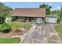 Inviting single-story home with a long driveway leading to a garage, surrounded by mature landscaping and a private yard at 40533 E 8Th Ave, Umatilla, FL 32784