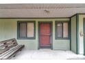 Covered front porch featuring a wooden bench, storm door and dark trim windows offering a welcoming entrance at 40533 E 8Th Ave, Umatilla, FL 32784