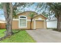 Tan single Gathering home featuring a palm tree, a 1-car garage, and a concrete driveway at 519 Beasley Ct, Orlando, FL 32807
