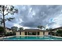 Community pool is open for a swim, flanked by a shady clubhouse and palm trees at 6108 Curry Ford Rd # 116, Orlando, FL 32822
