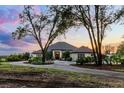 Beautiful home with mature trees, circular driveway, and stunning evening sky at 9019 Tower Pine Dr, Winter Garden, FL 34787