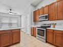 Well-lit kitchen with stainless steel range and microwave, featuring wooden cabinets and tile floors at 903 Tramells Trl, Kissimmee, FL 34744