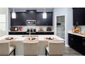 Modern kitchen featuring dark cabinets, a spacious island with barstool seating, and stainless steel appliances at 1852 Clear Sky Dr, Kissimmee, FL 34744