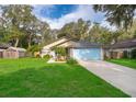 Single story home with a blue garage door, well-manicured lawn, and lovely landscaping at 39939 Parkinsonia St, Lady Lake, FL 32159