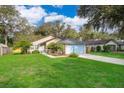 Beautifully landscaped single-story home with a blue garage door and a green front lawn at 39939 Parkinsonia St, Lady Lake, FL 32159