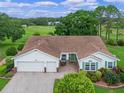 Well-maintained home featuring a two-car garage, brick accents, tidy landscaping, and outdoor seating at 4830 Summerbridge Cir, Leesburg, FL 34748