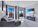 Stylish living room featuring a comfortable couch, balcony access, and a modern entertainment unit at 6165 Carrier Dr # 2605, Orlando, FL 32819