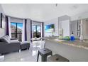 Modern living room with stainless steel appliances, a sleek couch, and balcony access at 6165 Carrier Dr # 2605, Orlando, FL 32819