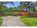 Inviting red home with a long driveway, mature trees, and well-maintained lawn at 874 Quarters Ct, Port Orange, FL 32129