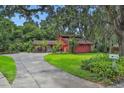 Beautiful home surrounded by mature trees, featuring a paved driveway and lush green lawn at 874 Quarters Ct, Port Orange, FL 32129