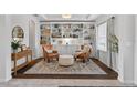 Cozy living room with hardwood floors, two leather chairs, ottoman, rug, and a wall of built-in bookshelves at 15318 Sandfield Loop, Winter Garden, FL 34787