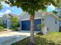 Exterior side view showcasing the attached two-car garage with blue door and well-maintained lawn at 2474 Cimmaron Ash Way, Apopka, FL 32703