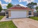 Attractive single-story home featuring a two-car garage, well-kept lawn, and neat landscaping at 10360 Crystal Point Dr, Orlando, FL 32825