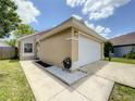 Inviting single-story home with a two-car garage, manicured lawn, and decorative rock features at 10360 Crystal Point Dr, Orlando, FL 32825