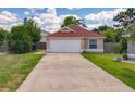 Charming single-story home with a well-maintained lawn, long driveway, and attached two-car garage at 10360 Crystal Point Dr, Orlando, FL 32825