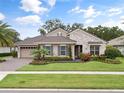 Charming single-Gathering home showcasing stone accents, a manicured lawn, colorful flowerbeds, and a paved driveway at 1265 Estancia Woods Loop, Windermere, FL 34786