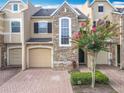 Charming townhome with a brick driveway and a crepe myrtle tree with bright pink blooms at 15822 Woodland Spring Ct, Orlando, FL 32828