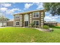 Two-story home displaying a well-maintained lawn, brick-lined flower bed, and inviting curb appeal at 16012 Lanesboro Ct, Clermont, FL 34711