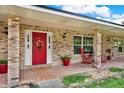 Inviting front porch with brick pillars, rocking chairs, and a red front door with wreath at 1778 Woodcrest Ln, Deland, FL 32720