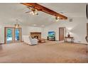 Open living room featuring a brick fireplace, ceiling fans, neutral carpet, and french doors to the pool at 1778 Woodcrest Ln, Deland, FL 32720