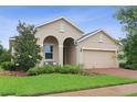 Charming beige home featuring a brick driveway, arched entryway, and well-maintained landscaping at 2339 Jernigan Loop, Kissimmee, FL 34746