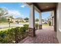 Inviting covered porch with brick flooring, stone-based columns, and lush landscaping at 4759 Riverwalk Dr, St Cloud, FL 34771