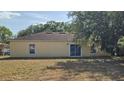 Exterior back of home with sliding glass doors, windows, and large grassy yard surrounded by trees at 607 Escondido Ct, Kissimmee, FL 34758