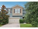 Two story home with a beige two-car garage, manicured landscaping, and a decorative tree in the front yard at 16440 Centipede St, Clermont, FL 34714