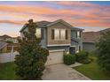Two story home with a beige two-car garage, manicured landscaping, and a decorative tree in the front lawn at 16440 Centipede St, Clermont, FL 34714