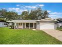 Inviting home with a well-manicured lawn, attached garage, and covered porch with bright white accents at 2050 Anne Cir, South Daytona, FL 32119