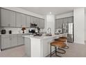 Modern kitchen boasts gray cabinets, stainless steel appliances, quartz countertops, and breakfast bar seating at 2927 Believe In Yourself Ct, Clermont, FL 34714