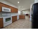 Well-equipped kitchen features white appliances, wooden cabinets, and view into the adjacent living spaces at 5515 Paradise Cay Cir, Kissimmee, FL 34746