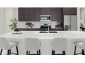 Modern kitchen featuring an island with white countertops, stainless steel appliances, and dark brown cabinets at 5656 Vinyasa Rd, Clermont, FL 34714