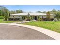 A single-story home on a lush green lawn with mature landscaping, a metal roof, and a paved circular driveway at 920 Grand Ave, Orange City, FL 32763
