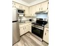 Modern kitchen featuring stainless steel appliances, granite countertops, and stylish wood-look flooring at 10301 Us Highway 27 # 34, Clermont, FL 34711