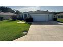 Charming single-story home with a well-manicured lawn, long driveway, and two-car garage at 13655 Se 97Th Terrace Rd, Summerfield, FL 34491