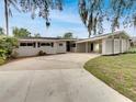 Single-story home with a spacious driveway and a unique carport, surrounded by lush landscaping at 2710 Wyndham Ln, Orlando, FL 32808