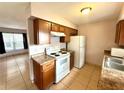Bright kitchen with wooden cabinets, white appliances, and tile flooring at 337 Live Oak Blvd, Sanford, FL 32773