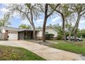 Exterior of a charming single-Gathering home with mature trees and a long driveway leading to an attached garage at 407 Ventura Dr, Sanford, FL 32773