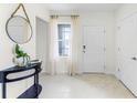 Bright entryway with neutral walls, tile floors, a decorative table, and a view through sheer curtains at 6006 Galloping Dr, Apopka, FL 32712