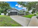 Home with a gray exterior, well-manicured lawn, and a spacious driveway leading to a two-car garage at 6609 Crenshaw Drive, Orlando, FL 32835