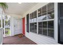 Inviting front porch with wood flooring, featuring a red front door and a charming window providing ample natural light at 824 Timor Ave, Orlando, FL 32804
