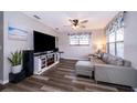 Cozy living room with a large television, comfortable gray sofa, ceiling fan, and stylish dark wood-look flooring at 824 Timor Ave, Orlando, FL 32804