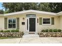 Close-up of the front entrance showcasing stone accents, green shutters and a modern black door with wreath at 1000 Kewannee Trl, Maitland, FL 32751