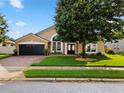 Traditional tan home featuring arched windows, a two-car garage, and a well-manicured front lawn at 1008 Soldier Creek Ct, Oviedo, FL 32765
