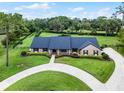 An aerial view of a brick home with a circular driveway and extensive landscaping on a large lot at 104 Amberwood Ct, Longwood, FL 32779