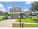 Charming two-story home with a well-manicured lawn, a two-car garage, and a light-blue front door at 11616 Thacker Dr, Clermont, FL 34711