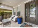 Inviting front porch with comfortable seating, potted plants, and a stylish door with decorative wreath at 14744 Spotted Sandpiper Blvd, Winter Garden, FL 34787